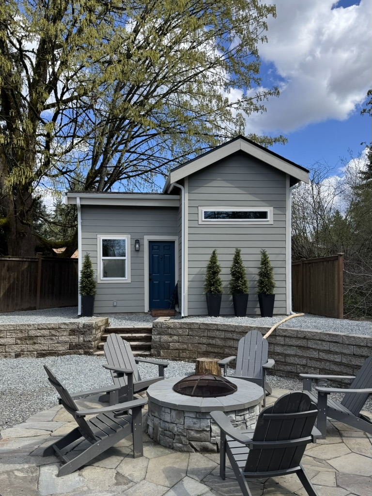 Back exterior of the completed 262 sqft tiny house ADU in Kent, WA with a fire pit and seating area at dusk
