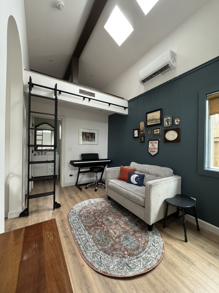 Living room of the 262 sqft tiny house ADU in Kent, WA featuring a sofa, framed gallery wall, and loft above