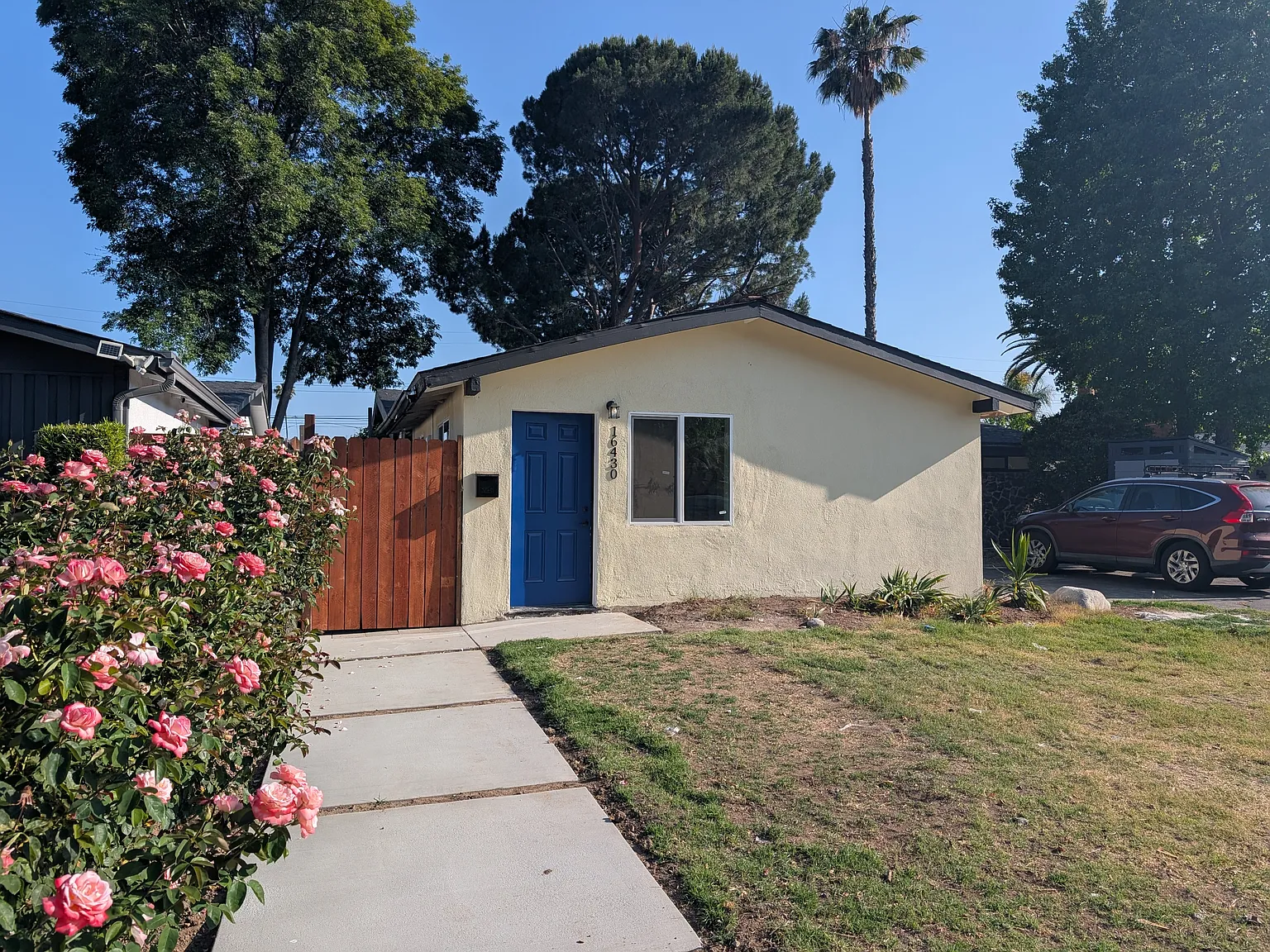 Charming California ADU with blue door, stucco exterior, and landscaped pathway