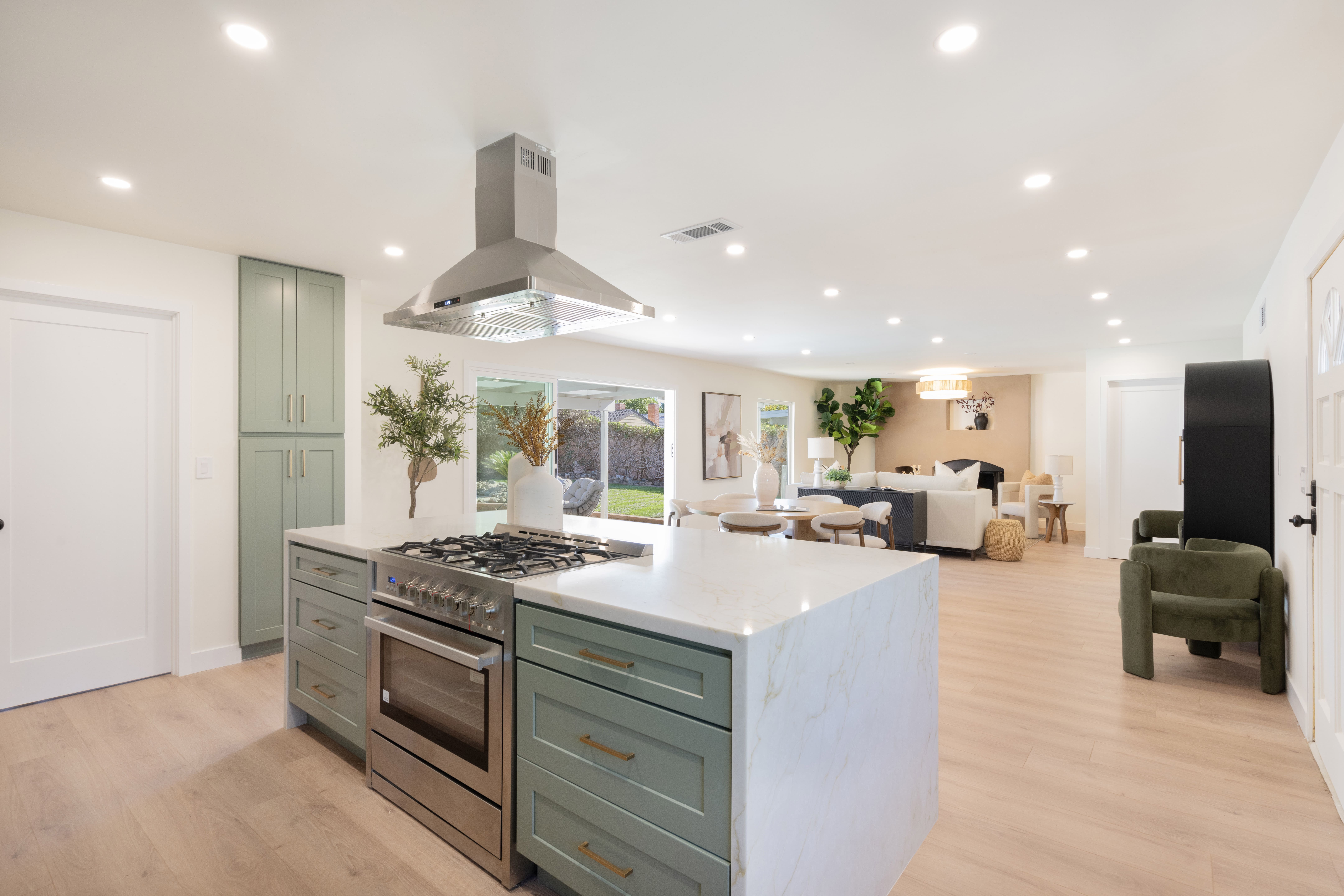 Luxury ADU open concept kitchen with sage green island, marble waterfall countertops, professional range, and open living area in California