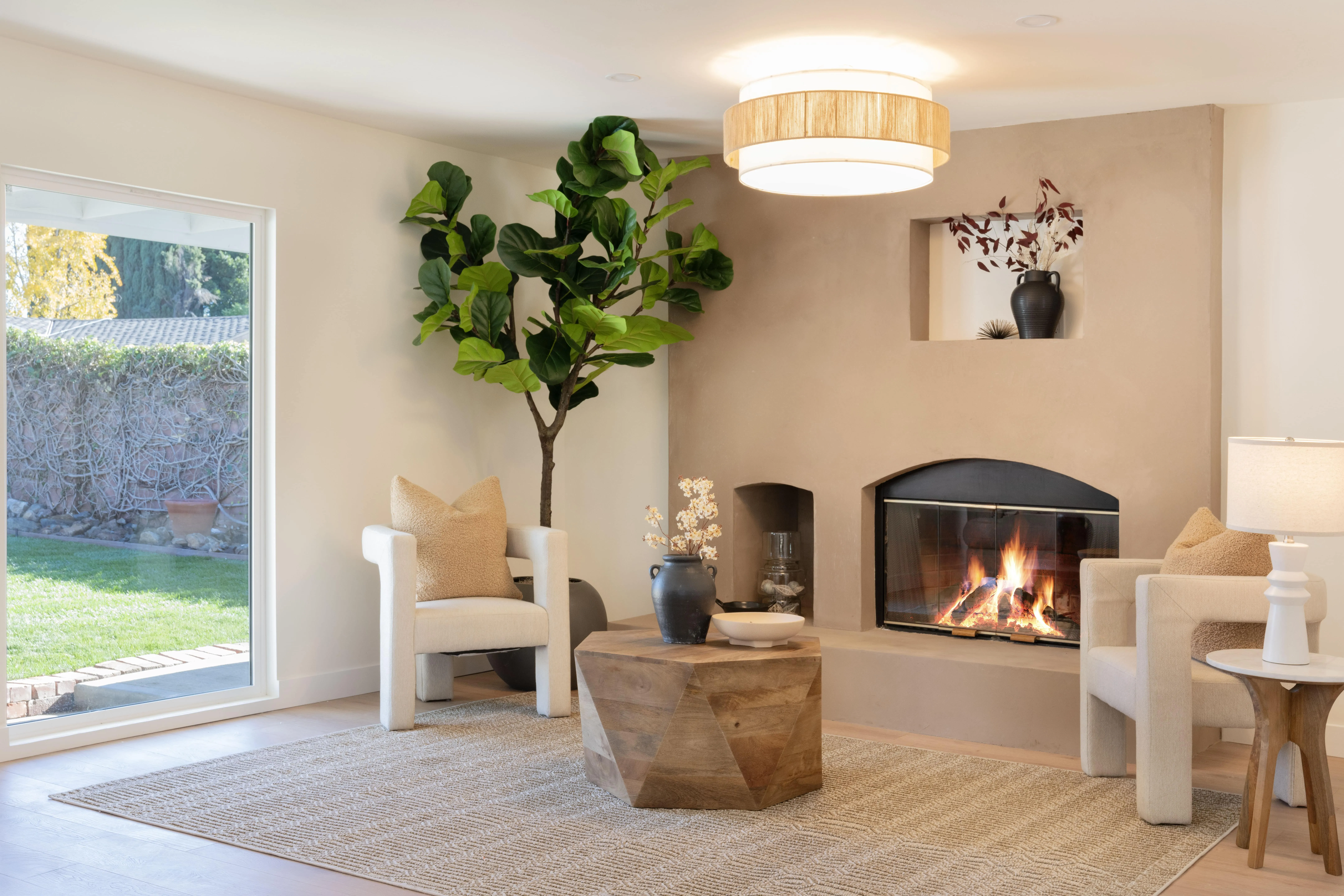 Cozy ADU living room with modern stucco fireplace, natural light, fiddle leaf fig plant, and designer furniture