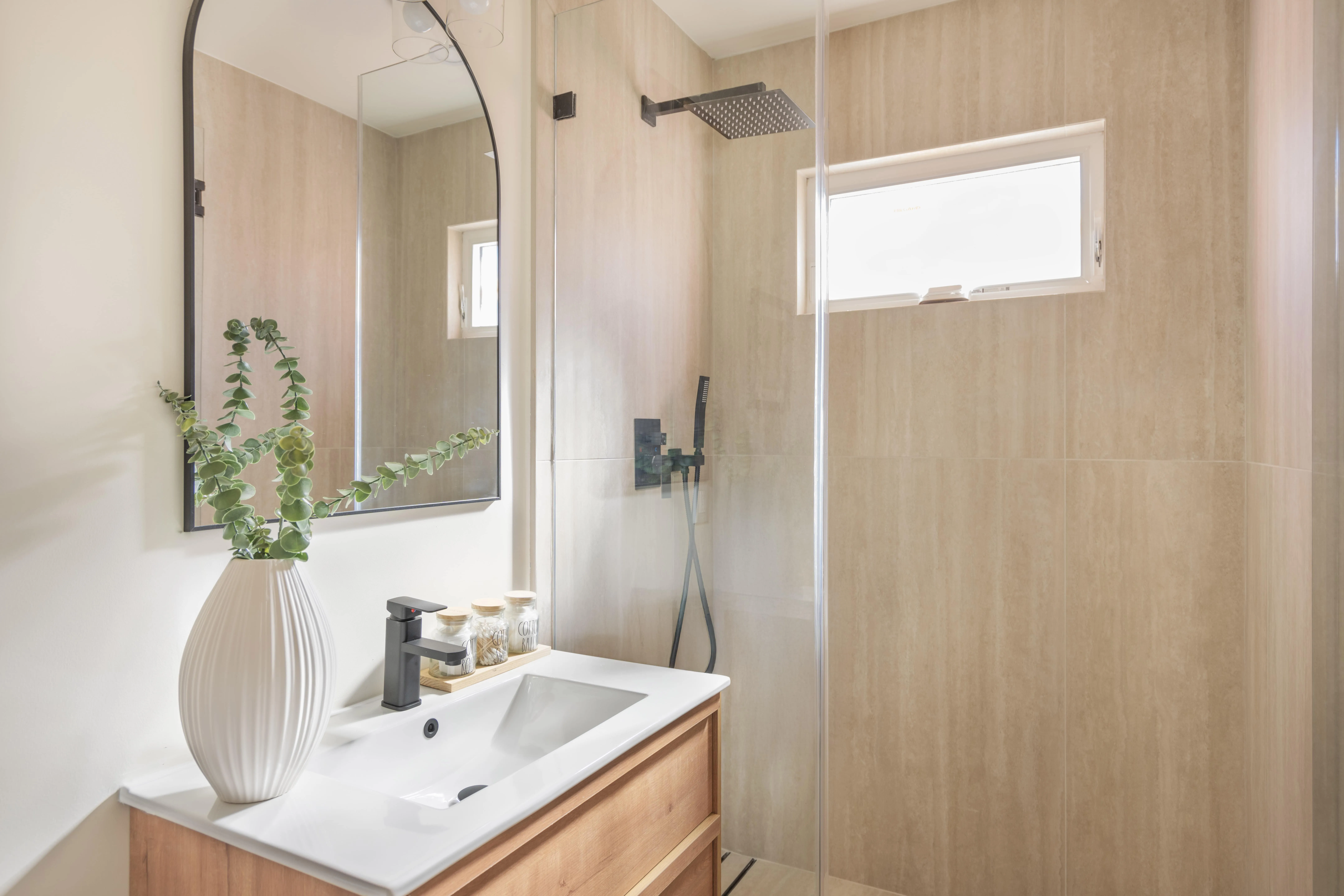 Complete ADU bathroom with wood vanity, walk-in shower, and natural light window